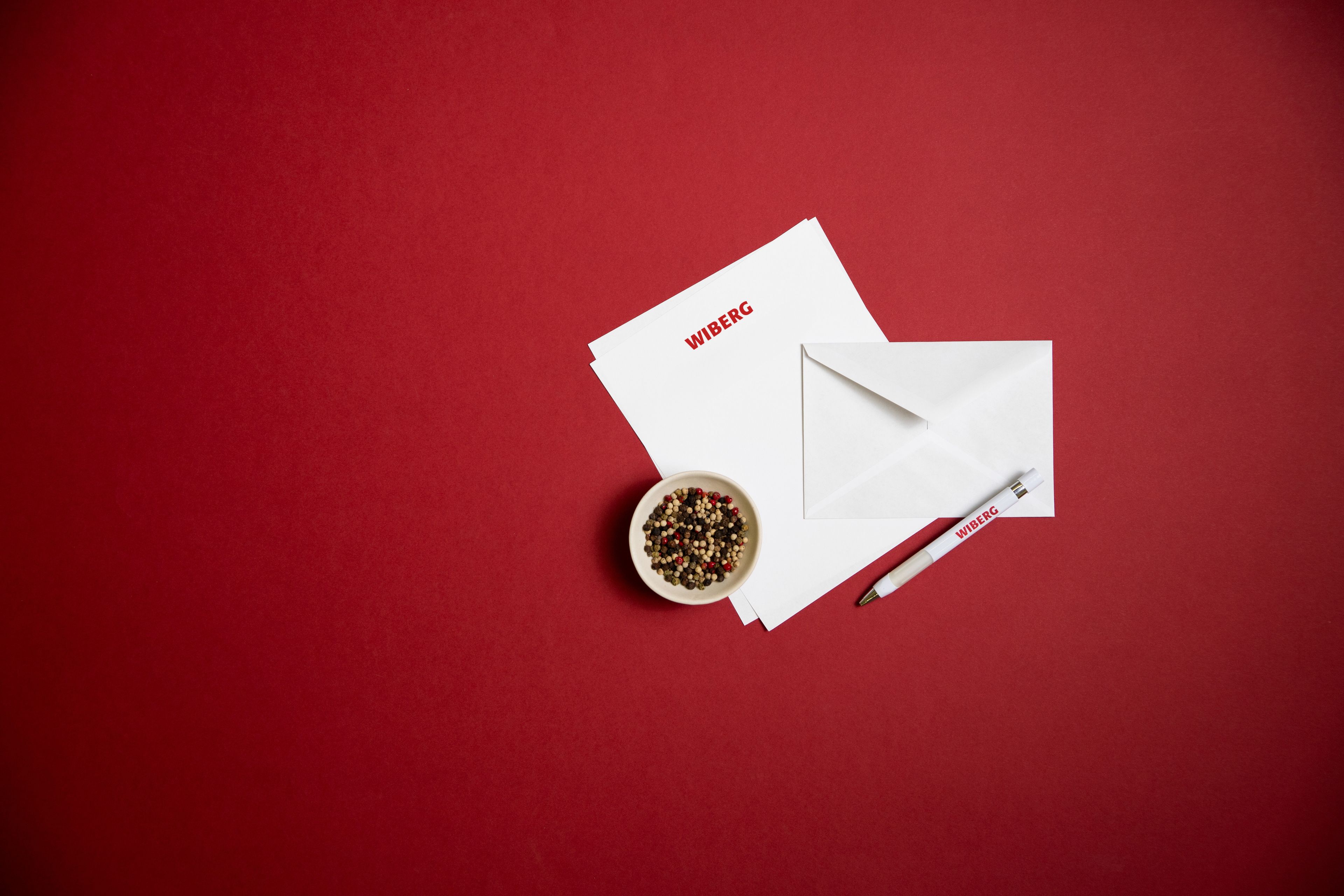 WIBERG Kontaktmotiv mit Briefumschlägen, Gewürzschale und Kugelschreiber auf rotem Hintergrund – persönliche Ansprechpartner für Profiköche.