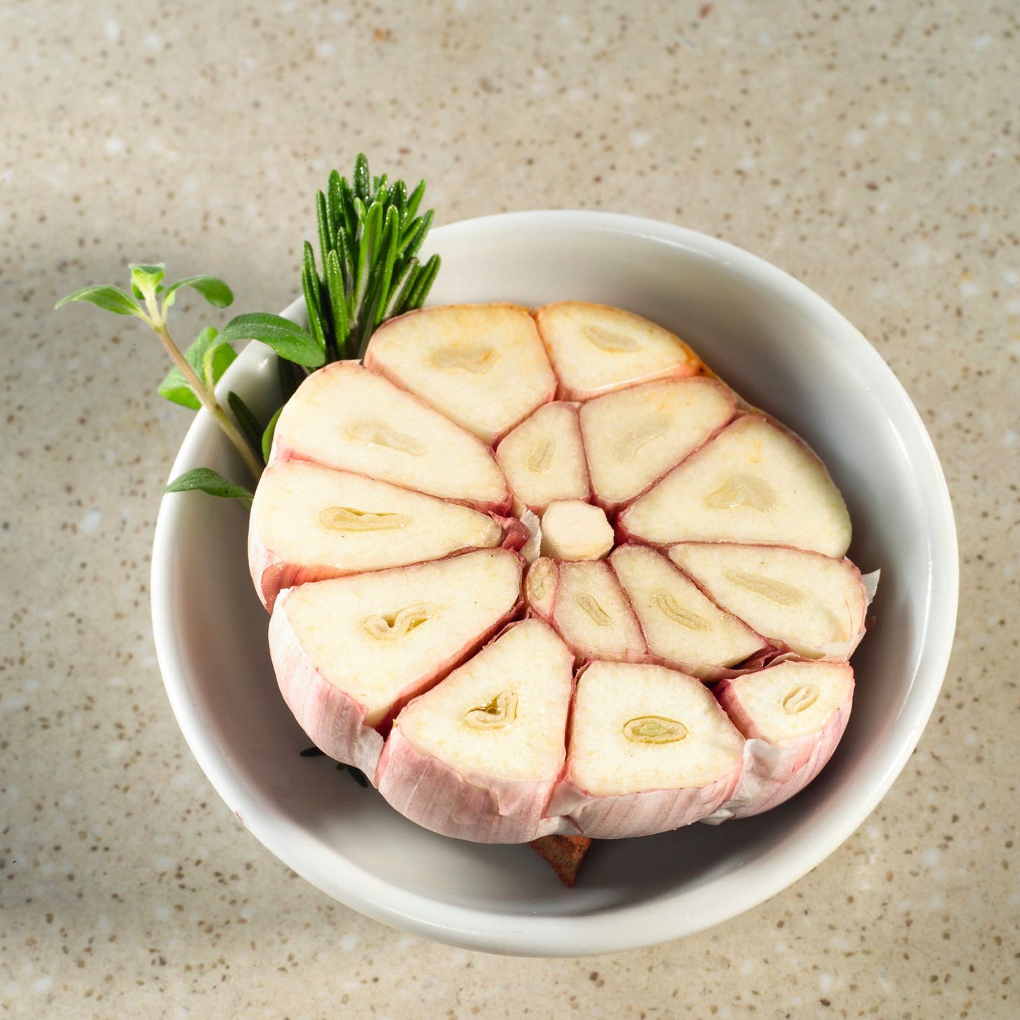 Aufgeschnittene Knoblauchknolle in einer Schale auf grauem Untergrund