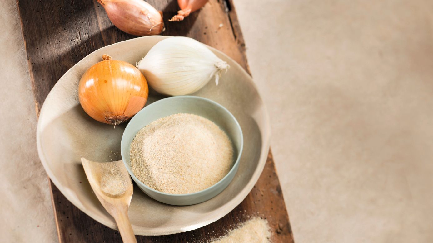 Ganze Zwiebeln und Zwiebelpulver in einer Schale