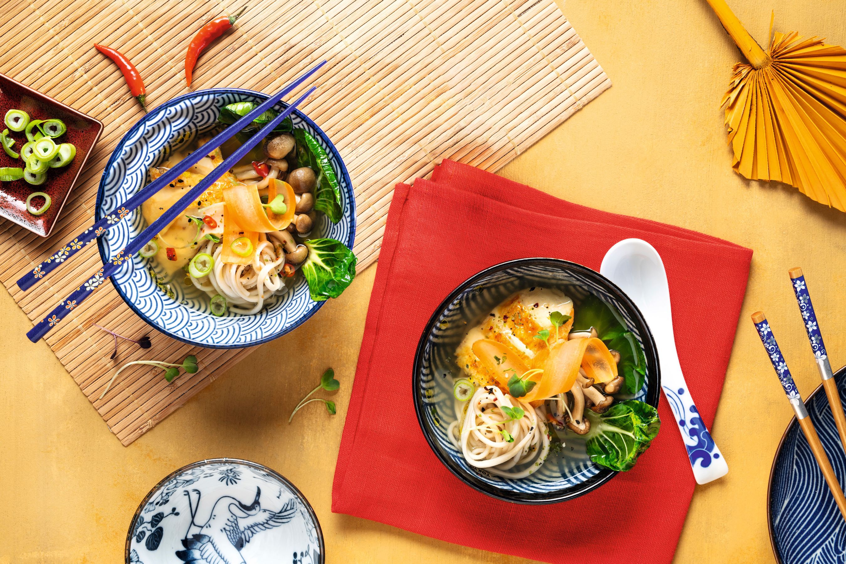  Querformataufnahme einer asiatischen Suppenschüssel mit Miso Suppe, Hühnchen und Sobanudeln auf asiatisch dekoriertem Tisch; kulinarische Inspiration von WIBERG.