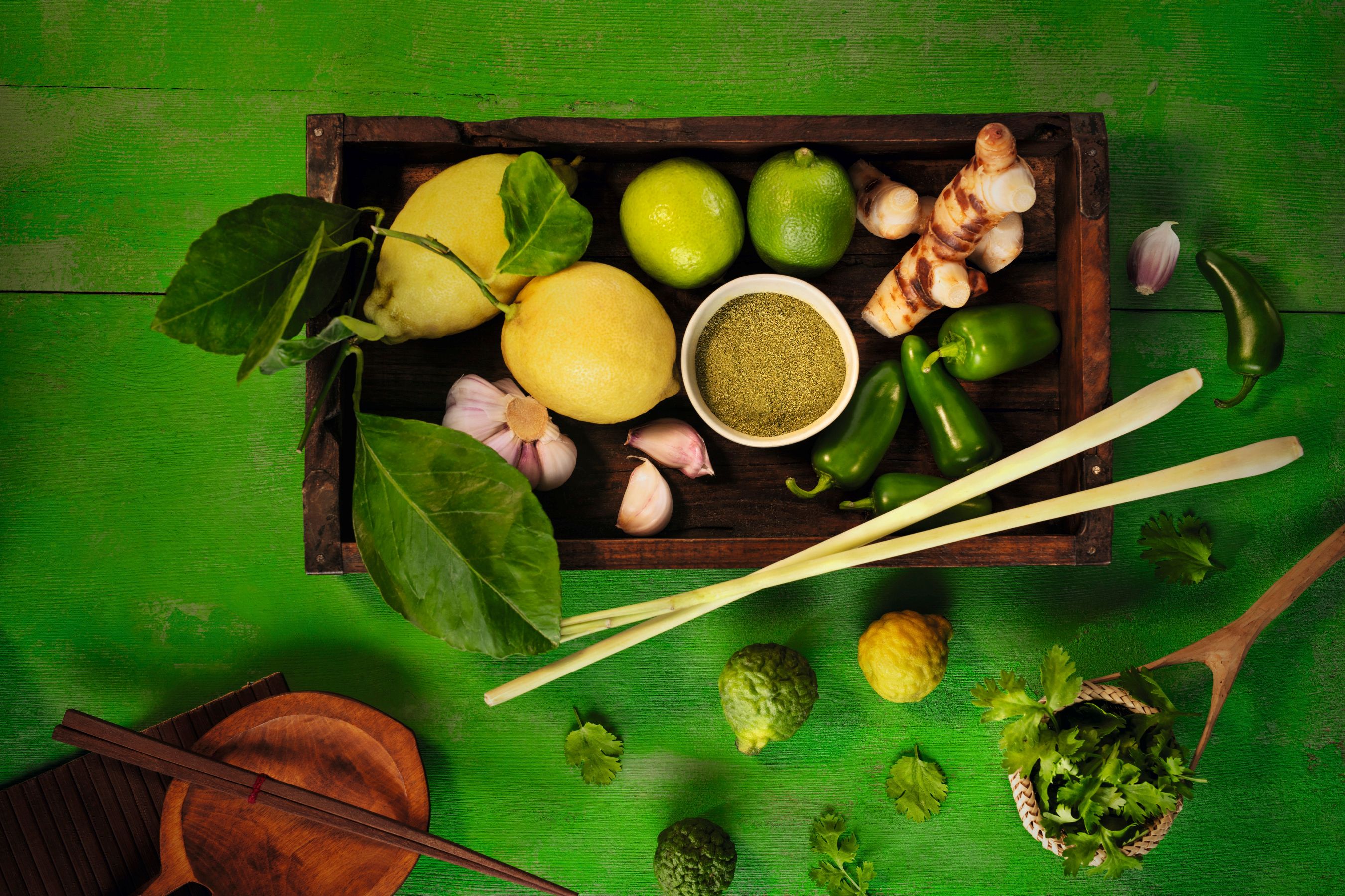 Querformat-Imagebild WIBERG Curry Grün auf strahlend grünem Hintergrund mit frischen Zutaten: Zitronen, Jalapeños, Kaffirlimette, Zitronengras, Ingwer, Knoblauch und Koriander – inspiriert von thailändischer Thai-Curry-Küche.