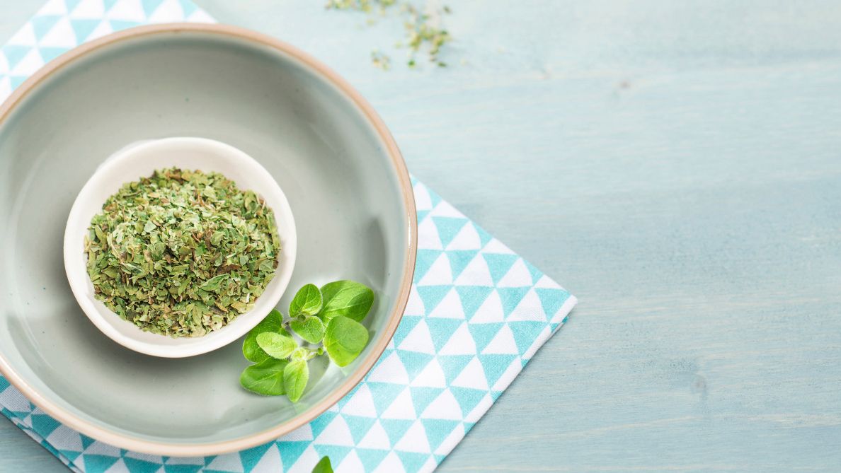 Getrockneter Oregano in einer weißen Schale mit frischen Oreganoblättern