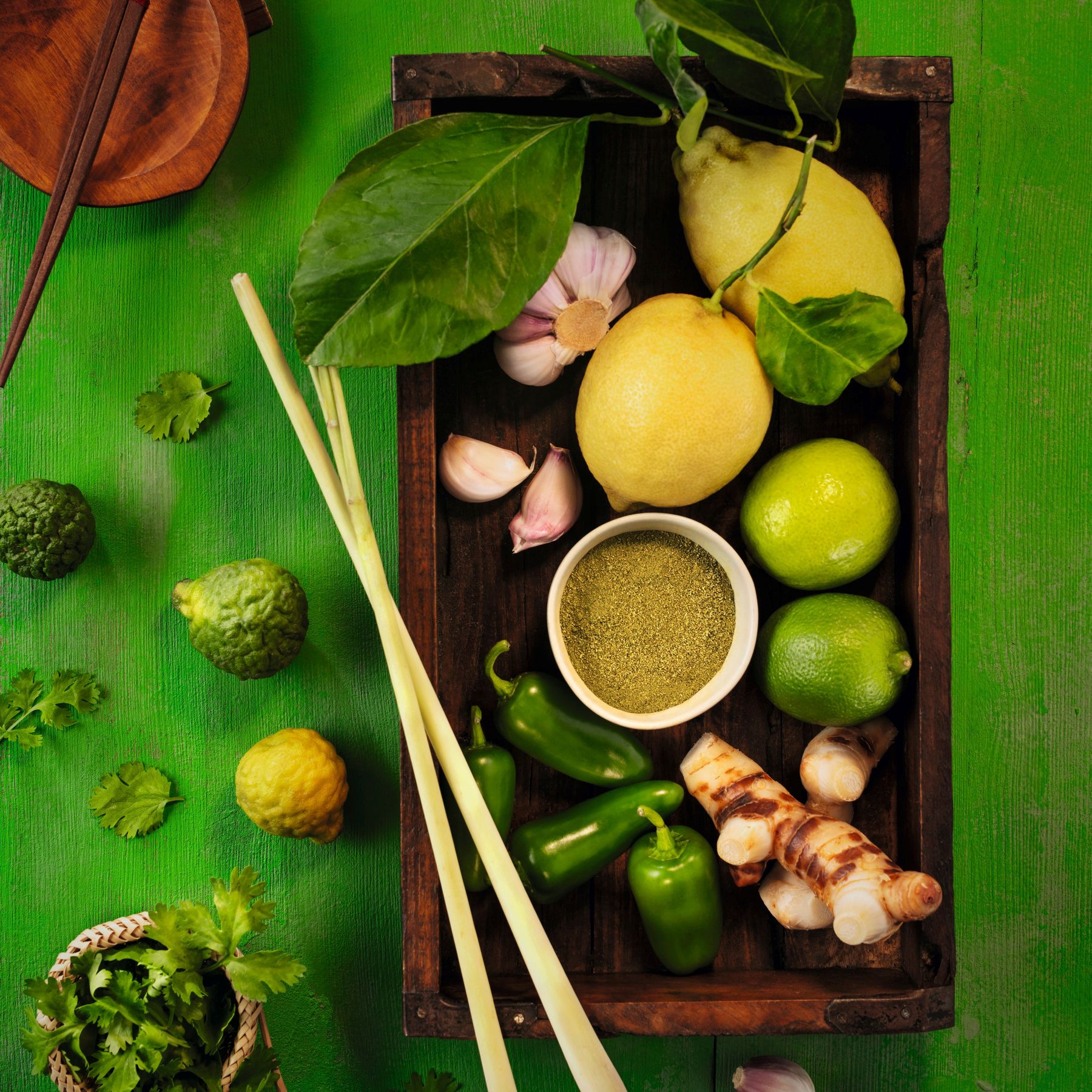Imagebild WIBERG Curry Grün auf strahlend grünem Hintergrund mit frischen Zutaten wie Zitronen, Jalapeños, Kaffirlimette, Zitronengras, Ingwer, Knoblauch und Koriander – inspiriert von thailändischer Curry-Küche.