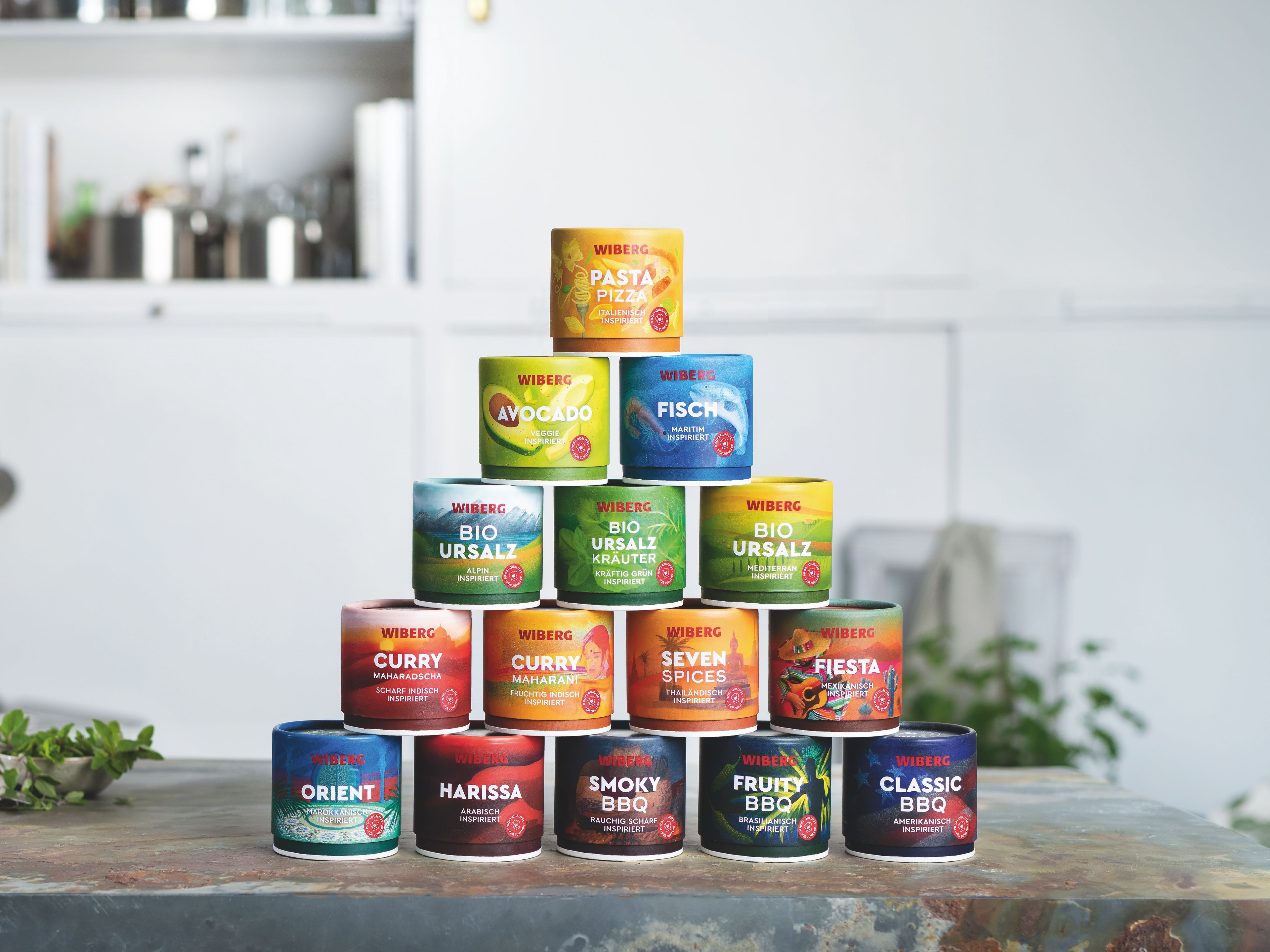 Pyramide aus 15 bunten WOW – World of WIBERG – Gewürzdosen in einer modernen hellen Küche, hochwertige Gewürzmischungen für zuhause.