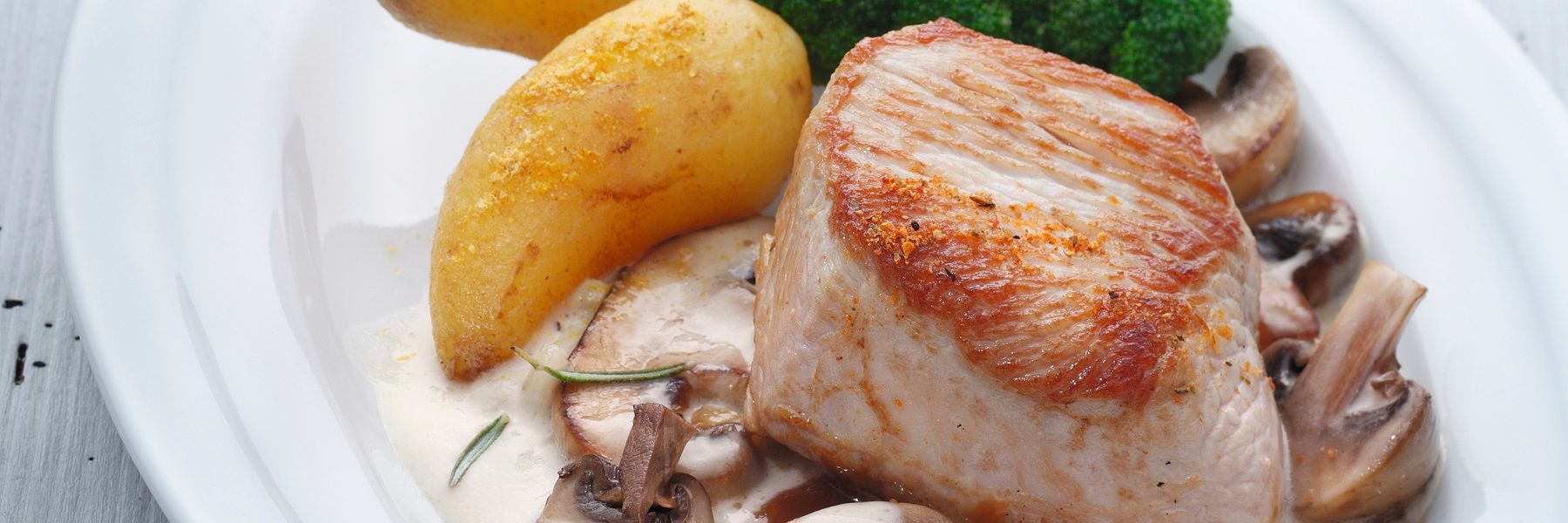 Heller Teller mit gebratenem Putensteak, Rahm-Pilzen, knusprigen Bratkartoffeln und Brokkoli – angerichtet mit WIBERG Gewürzen für die Profi-Küche.