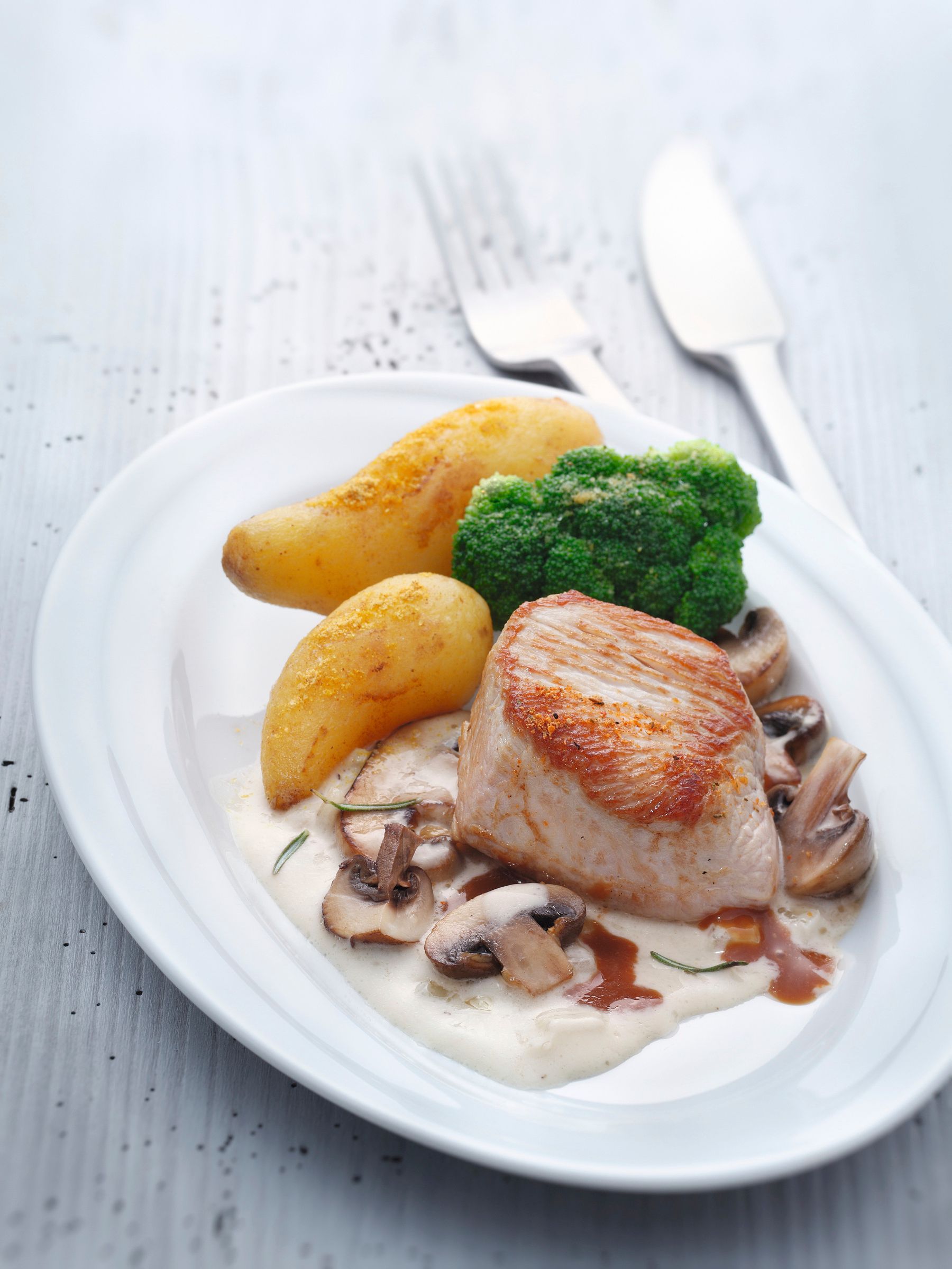 Heller Teller mit gebratenem Putensteak, Rahm-Pilzen, knusprigen Bratkartoffeln und Brokkoli – angerichtet mit WIBERG Gewürzen für die Profi-Küche.