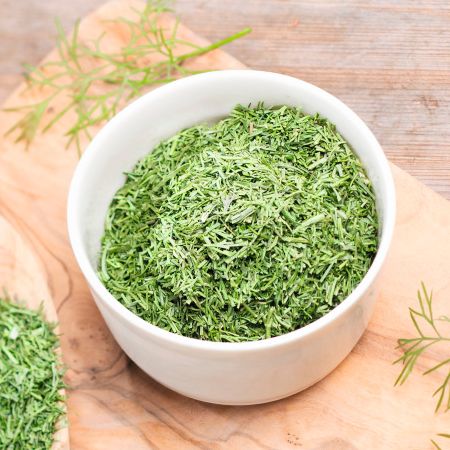 Getrockneter Dill in einer weißen Schale und auf einem Holzlöffel