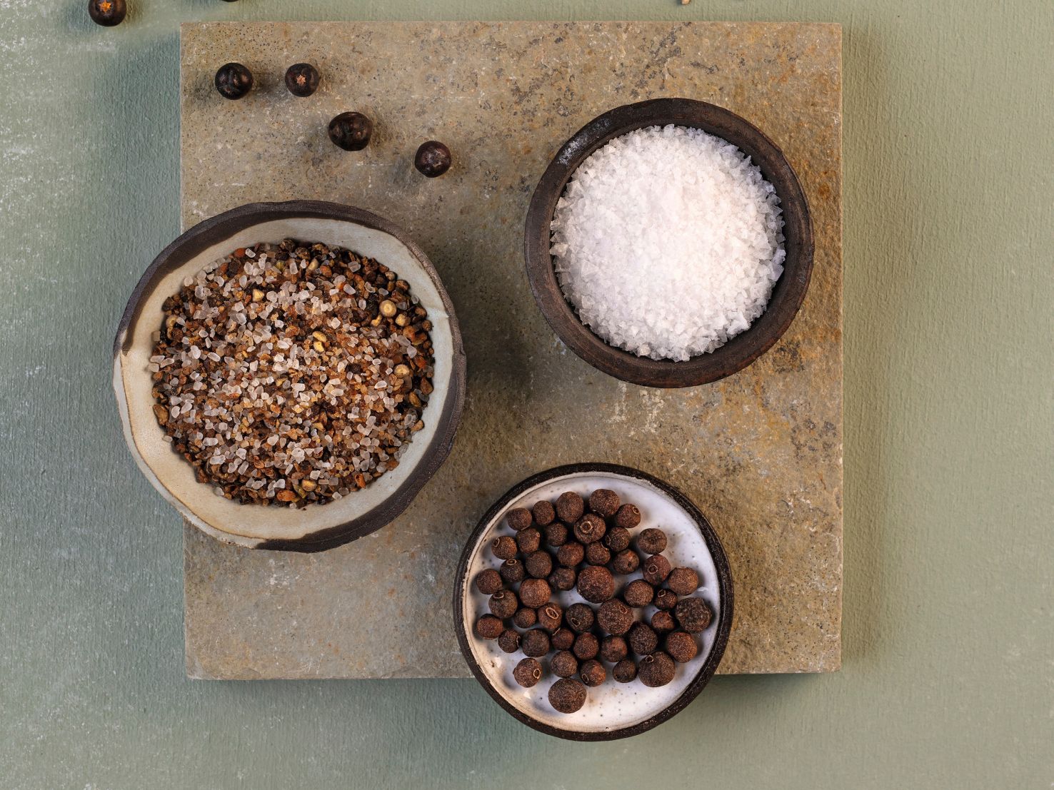 Symbolbild des WIBERG Rauchsalz-Mix in kleinen Schalen – geräuchertes Meersalz, Rohrohrzucker, Pfeffer, Piment und Wacholder als hochwertige Gewürzzutaten für Profiköche.
