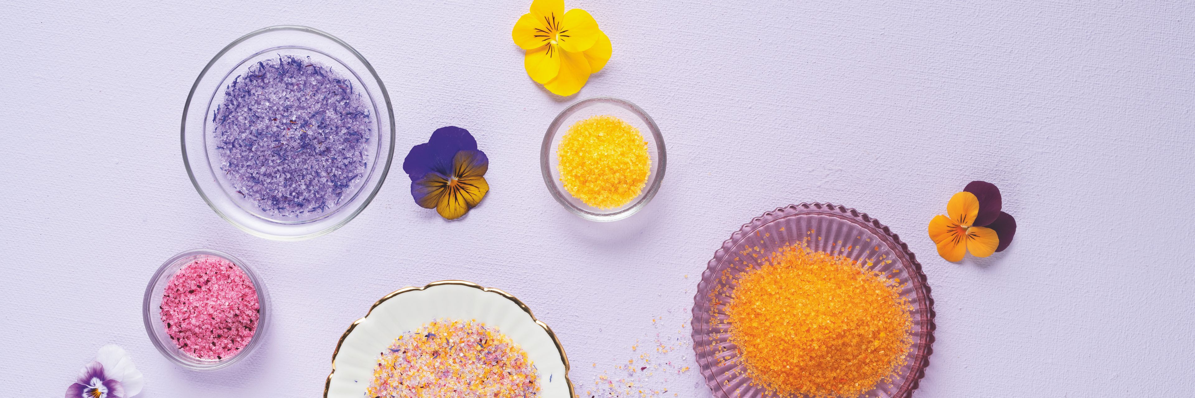  WIBERG Blütenzucker bunt auf helllila Hintergrund: farbenfrohe Blütenzucker-Mischung aus Tagetes-, Rosen-, Kornblumen- und Sonnenblumenblüten.