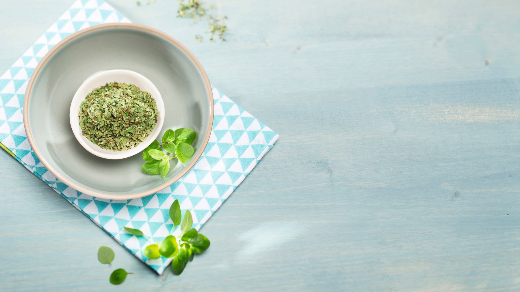 Getrockneter Oregano in einer weißen Schale mit frischen Oreganoblättern