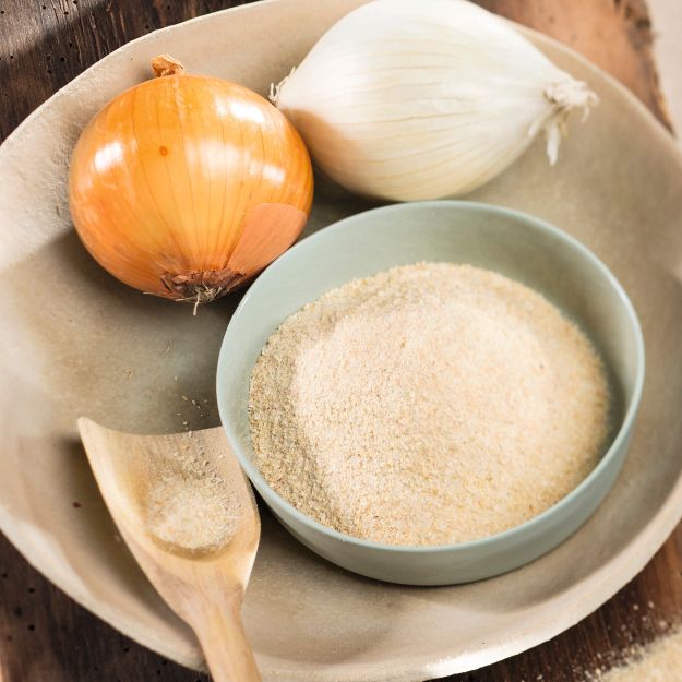 Ganze Zwiebeln und Zwiebelpulver in einer Schale