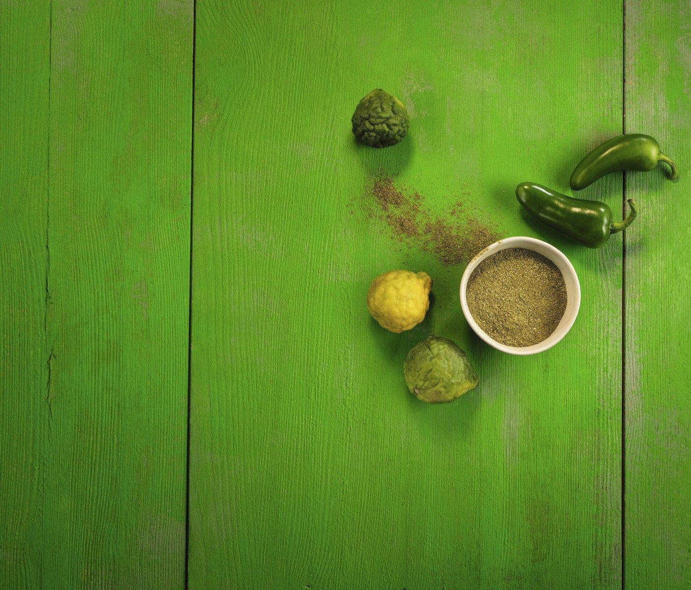 WIBERG Curry Grün auf strahlend grünem Hintergrund, arrangiert mit frischen Jalapeños und Kaffirlimette – inspiriert von thailischer Curry-Küche.